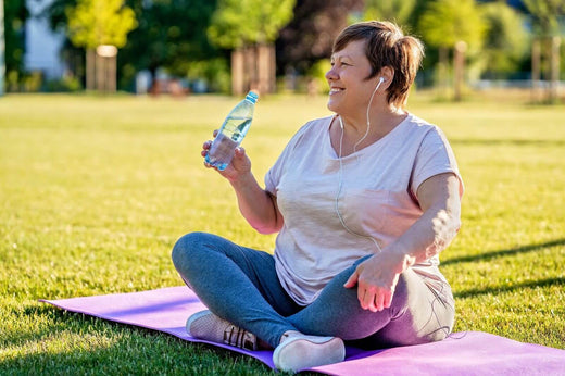 A woman smiling and drinking water.